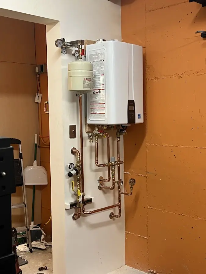 Plumbing technician inspecting water heater connections in Johnson Creek